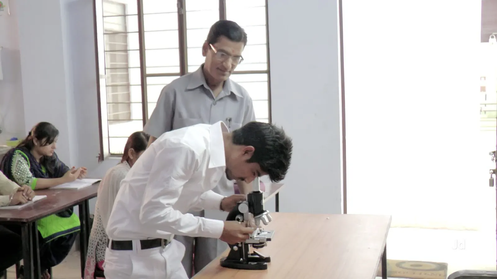 Student using a microscope under instructor guidance