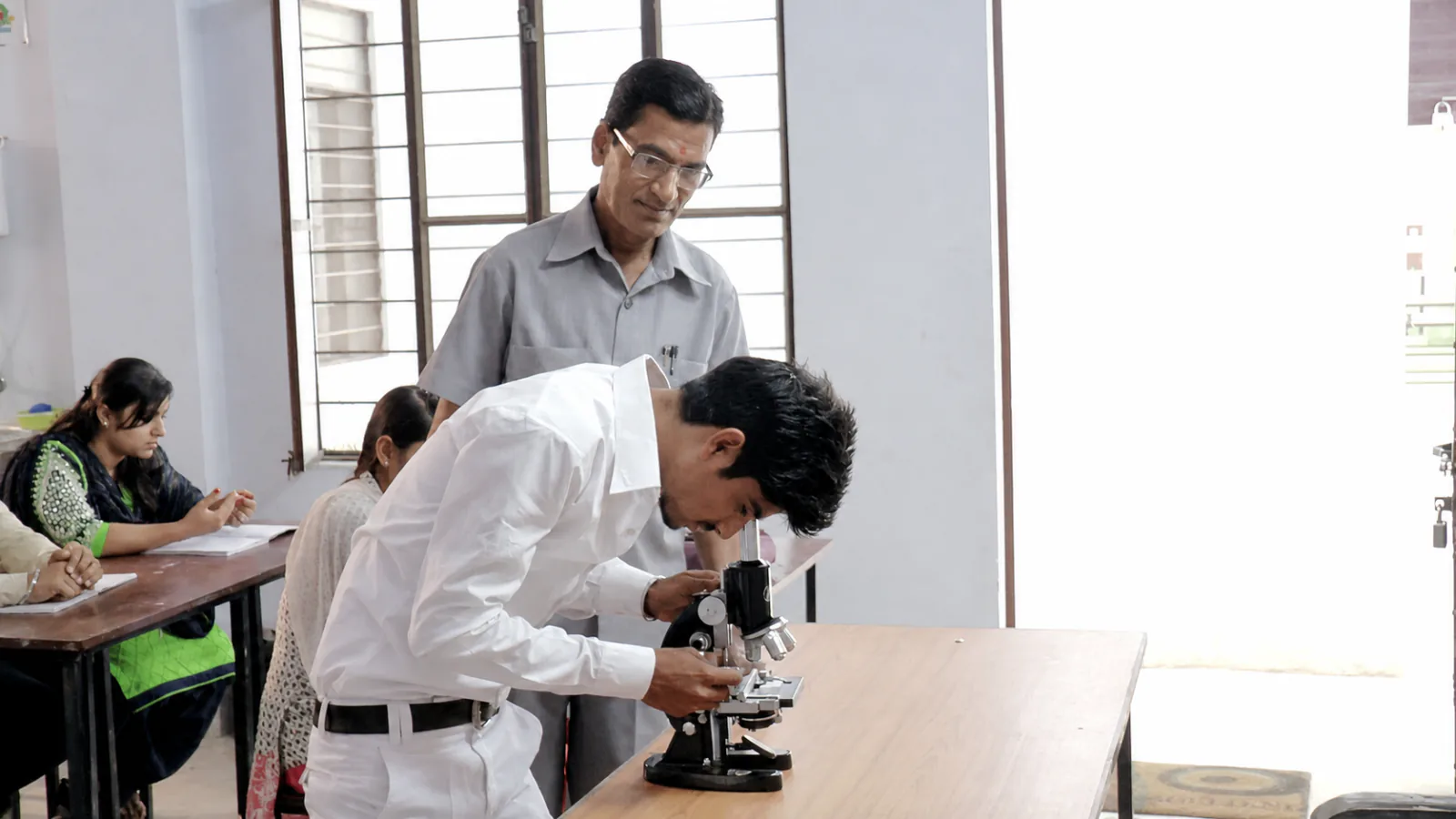 A Navodya ITI student using a microscope during supervised practical training